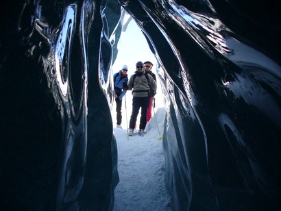 Caterina, Fulvio e Michele si affacciano all'ingresso di una grotta di ghiaccio naturale.